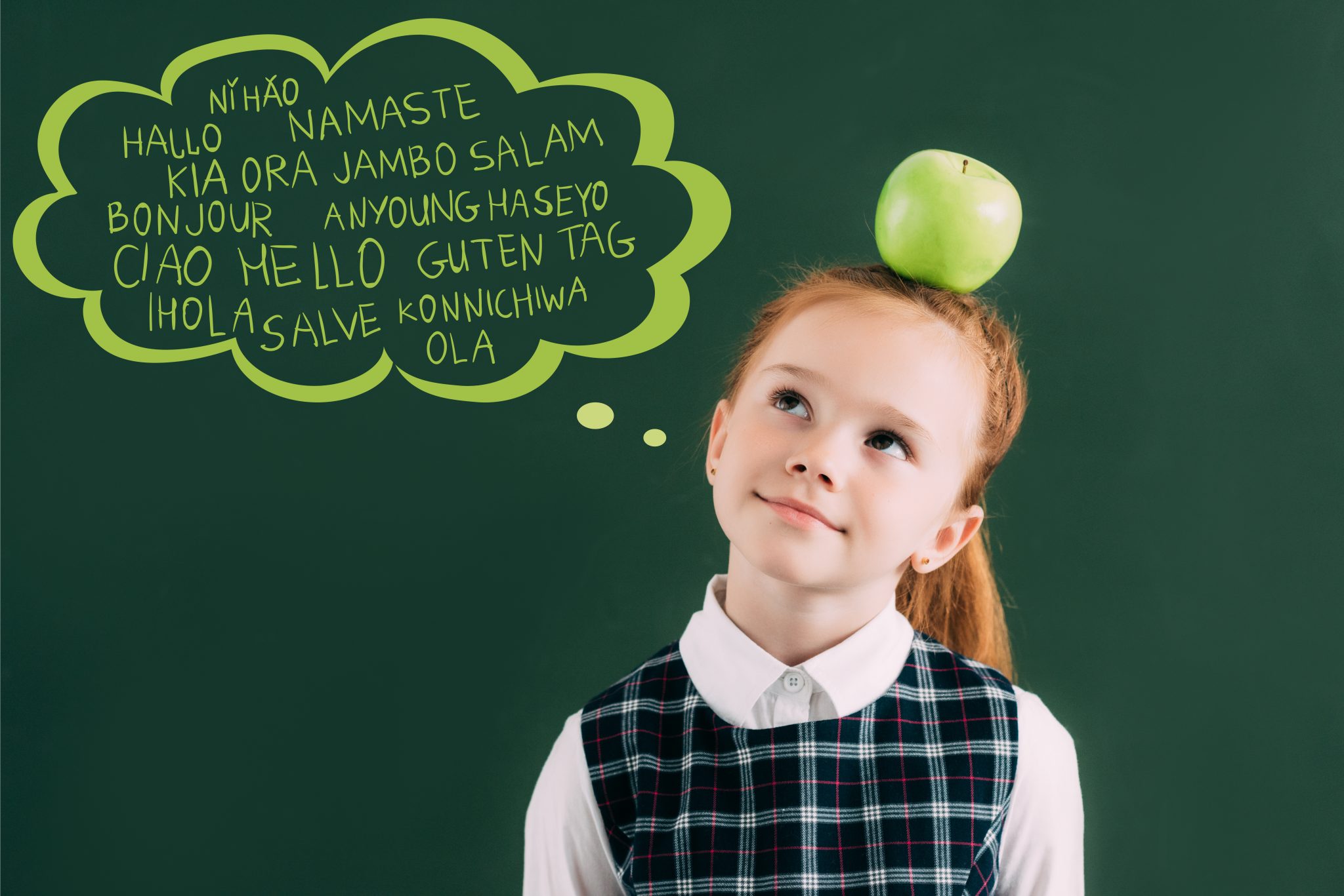 Une jeune fille rousse avec une pomme sur la tête se tient devant un panneau sur lequel est écrit Bonjour dans différentes langues. Par exemple en indien, allemand, japonais, anglais. Mais à chaque fois, il est écrit en alphabet latin. Dans les crèches de Butzemillen, une attention particulière est portée à l'apprentissage de plusieurs langues dès le plus jeune âge et donc à la compétence d'agir dans un environnement multilingue.